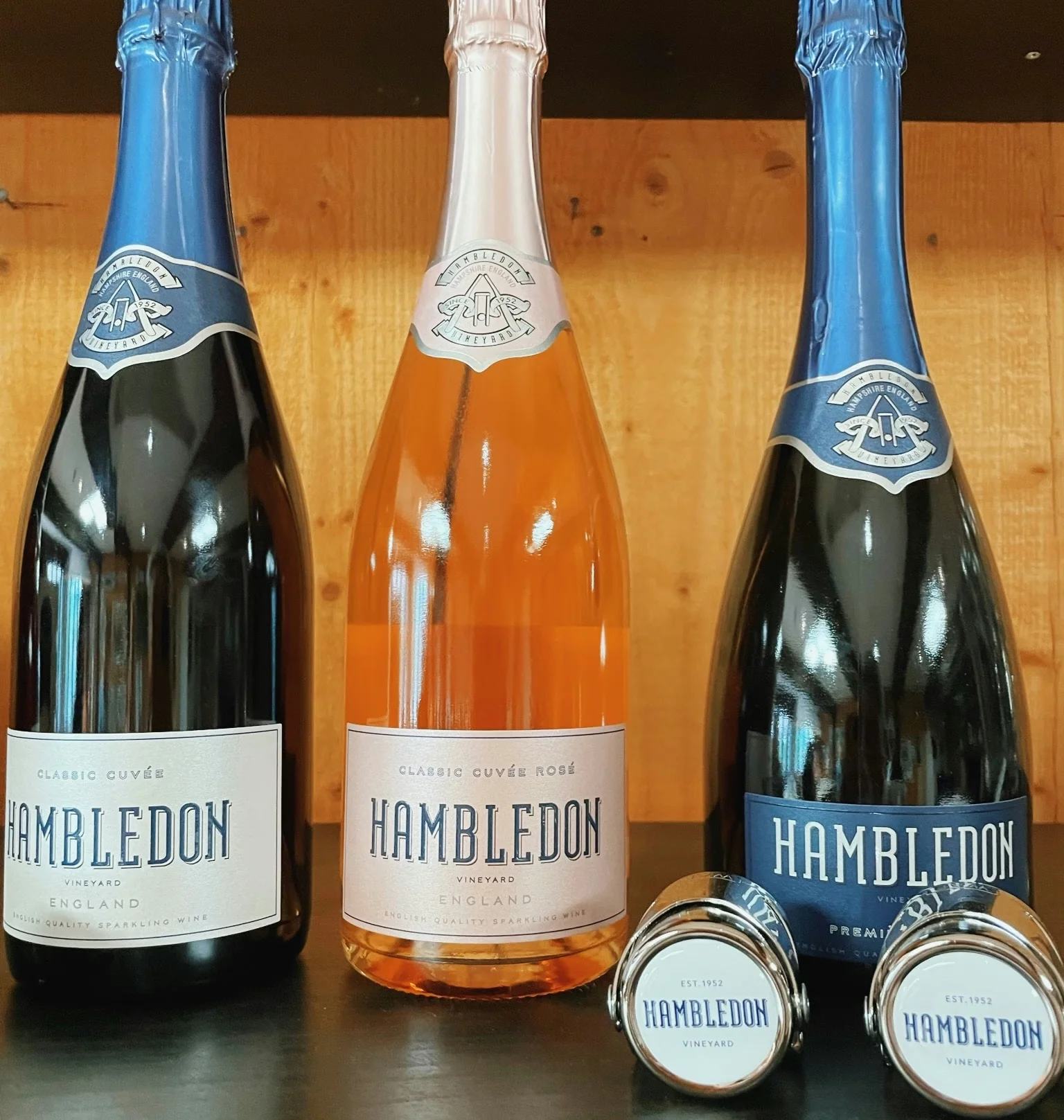 Three Hambledon sparkling wine bottles, including a rosé, with two branded wine stoppers