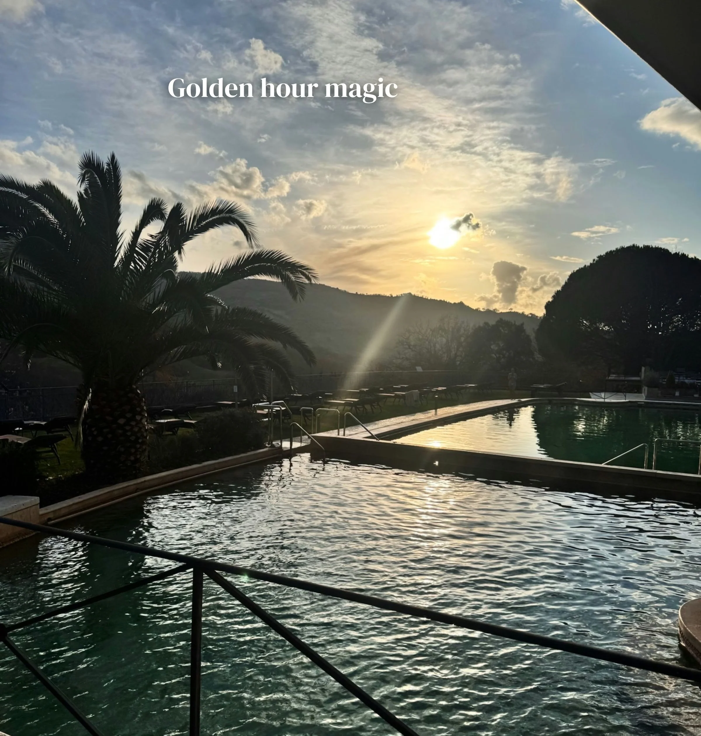 Outdoor pool at sunset with palm trees, hills and the words ‘Golden hour magic’