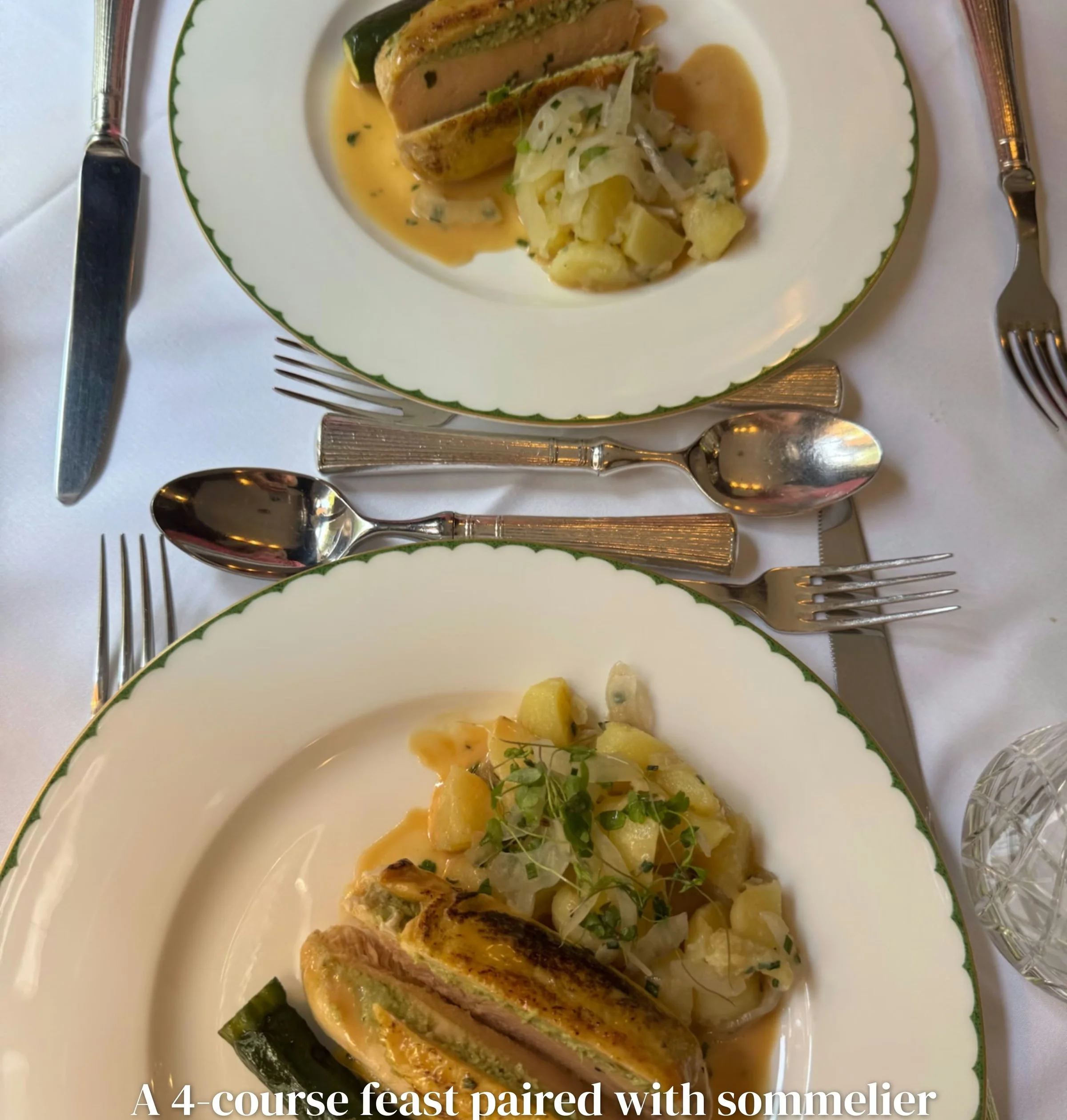 Two plated gourmet meals with vegetables and sauce on a formal white table setting