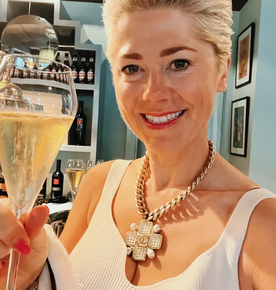 Smiling woman holding a glass of sparkling wine in a stylish bar interior