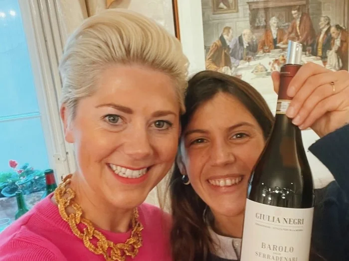 Two smiling women holding a bottle of Giulia Negri Barolo wine