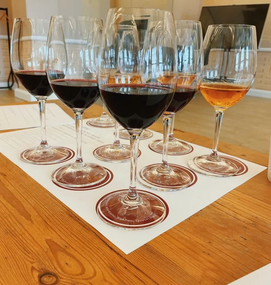 Wine tasting glasses filled with red, rosé and amber wine on labelled coasters