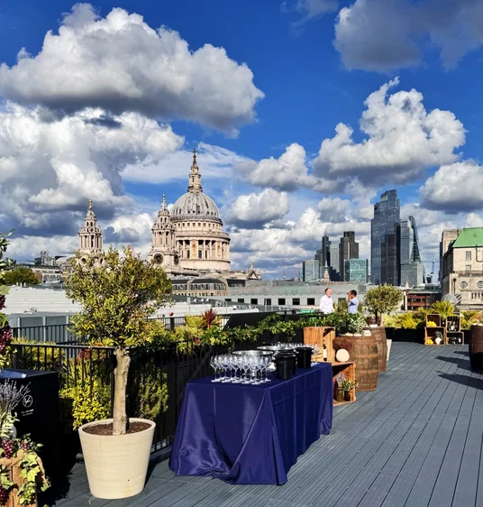 Rooftop wine tasting setup with glasses, plants and views of St Paul's Cathedral and London's skyline