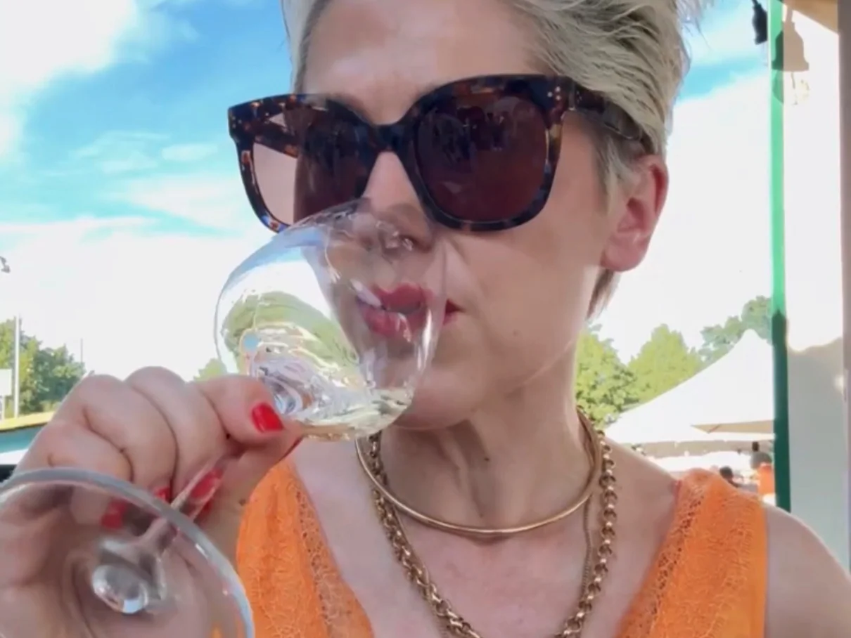 Woman in sunglasses tasting white wine outdoors at event