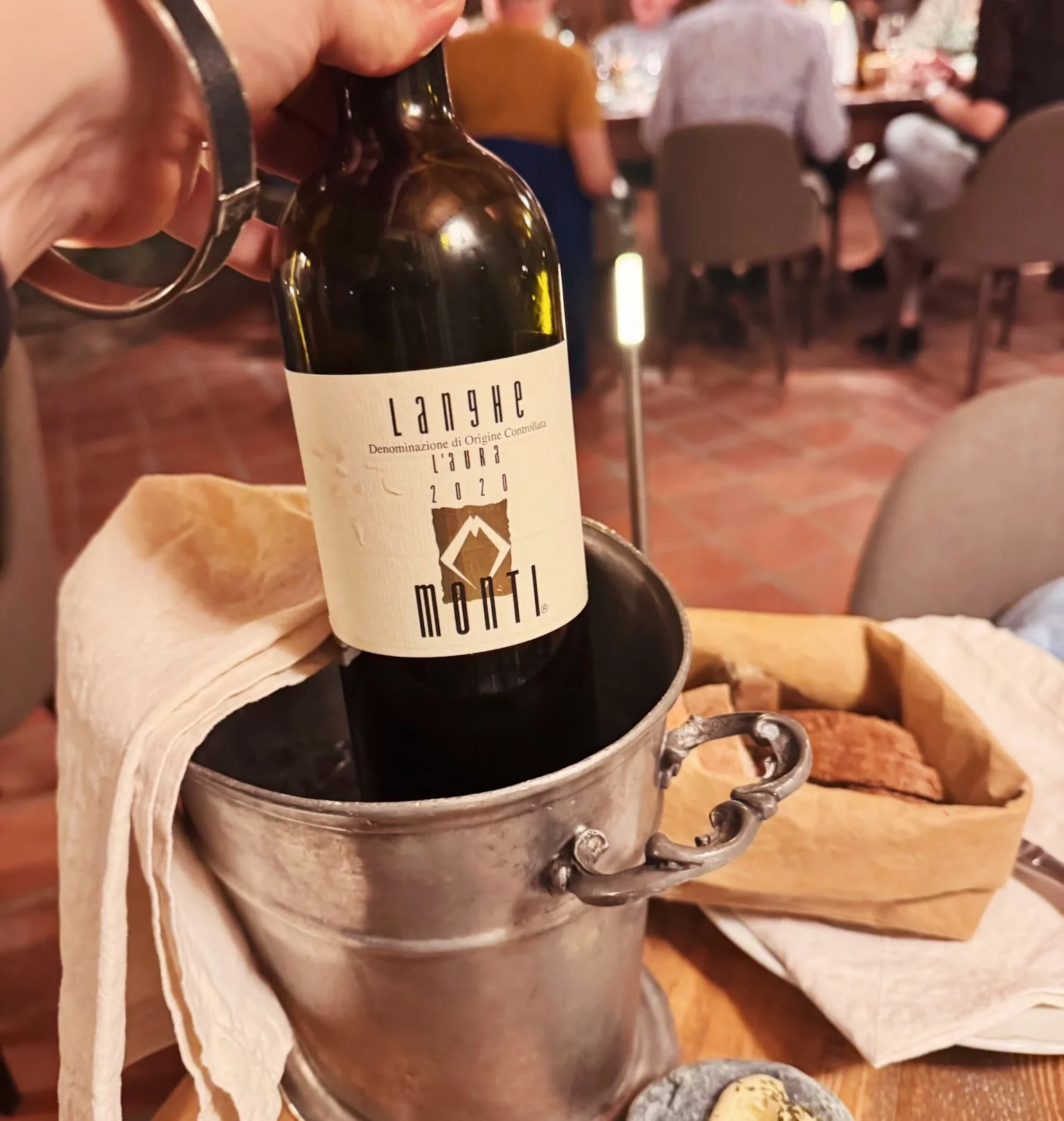Bottle of red wine in an ice bucket on a restaurant table, with bread and cheese beside it