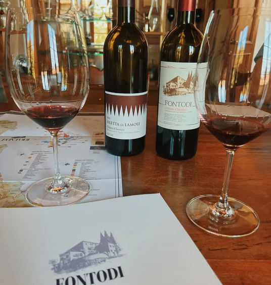 Two Fontodi Chianti Classico bottles and two glasses of red wine on a tasting table