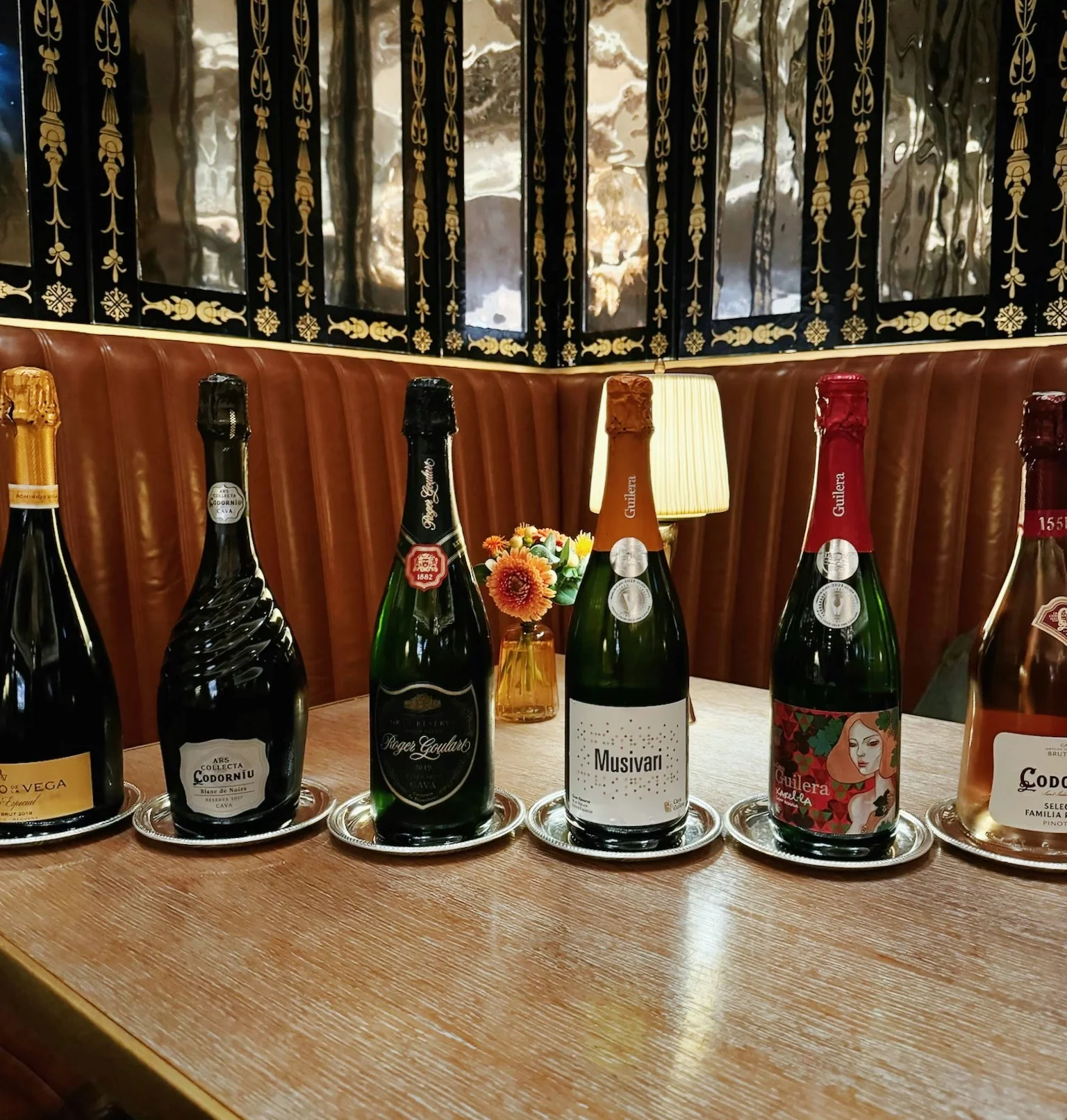Selection of Cava bottles displayed on silver trays in a restaurant booth