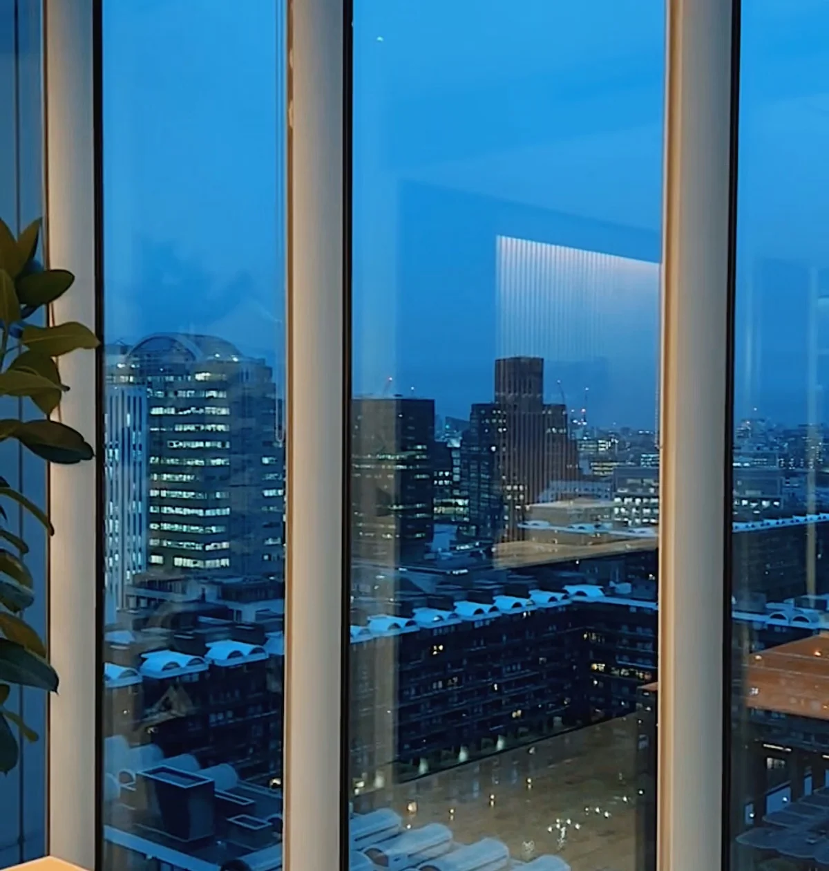 City skyline viewed through floor-to-ceiling windows at dusk