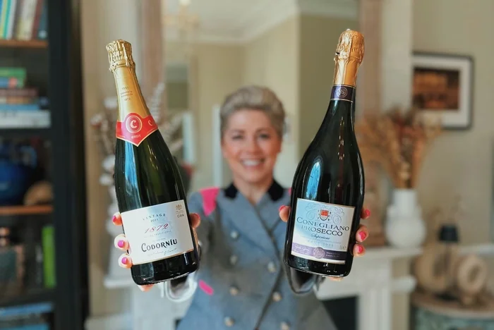 Woman holding two sparkling wine bottles indoors