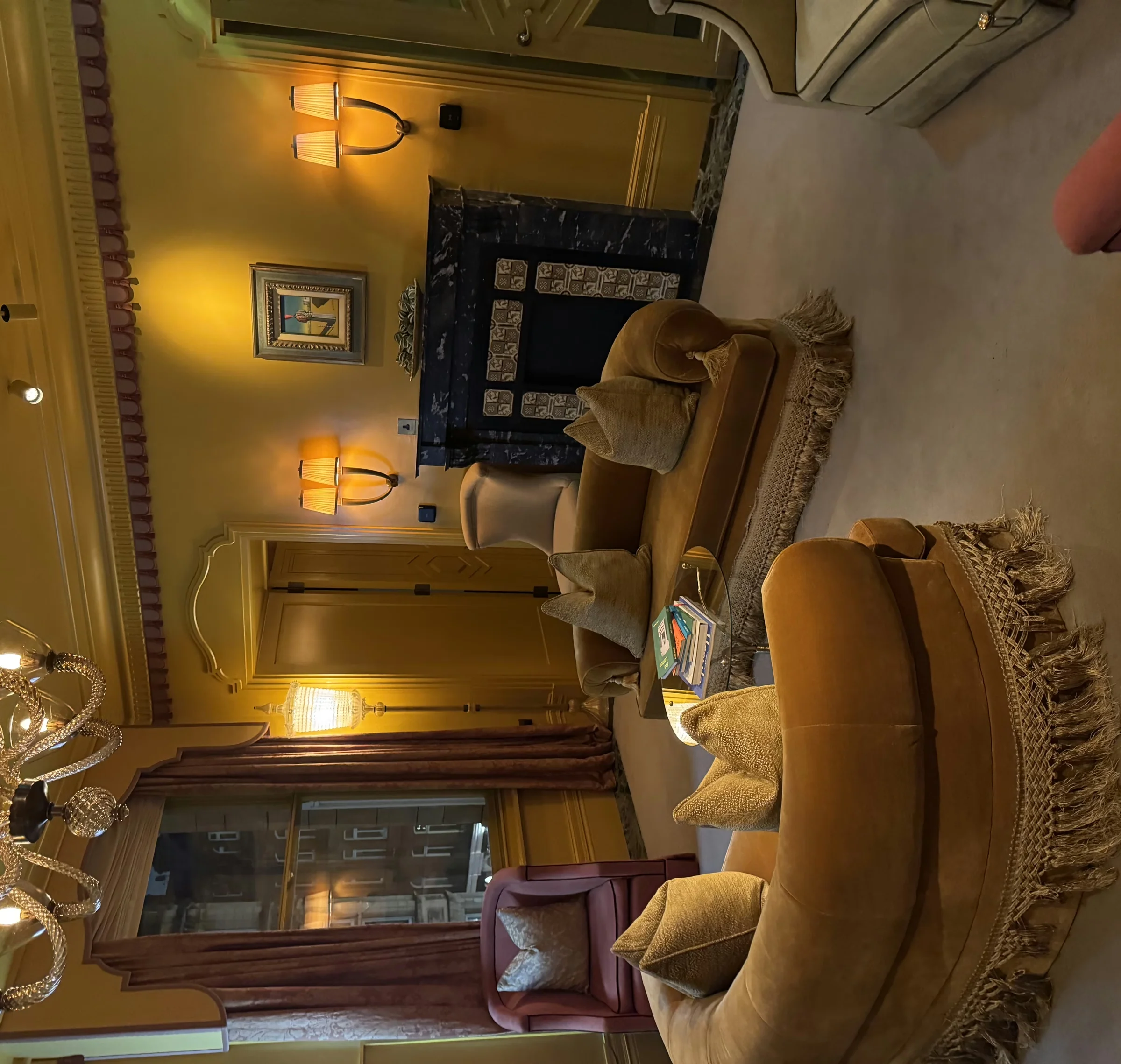 Elegant lounge with velvet sofas, fringed rugs, lamps, chandelier and fireplace in a London venue