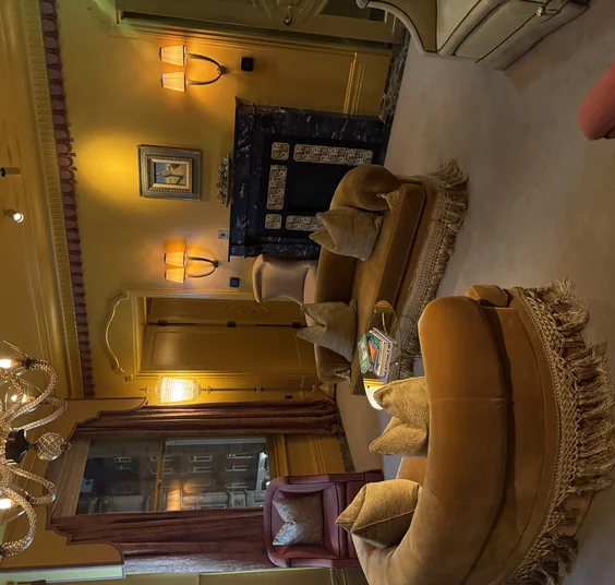 Elegant lounge with velvet sofas, fringed rugs, lamps, chandelier and fireplace in a London venue