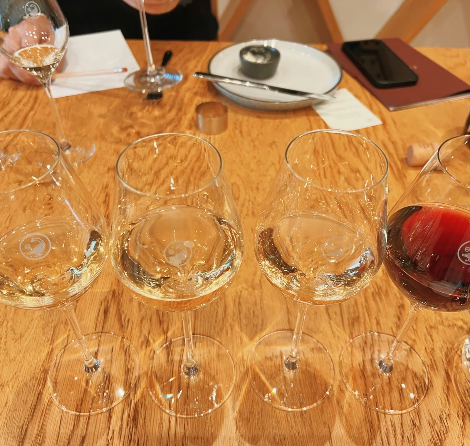 Four wine glasses containing three pale wines and one red wine on a tasting table