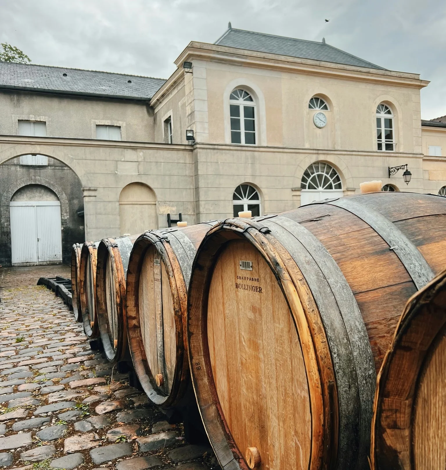 Large wooden Bollinger wine barrels outside a pale stone building