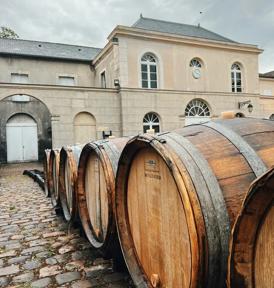 Large wooden Bollinger wine barrels outside a pale stone building