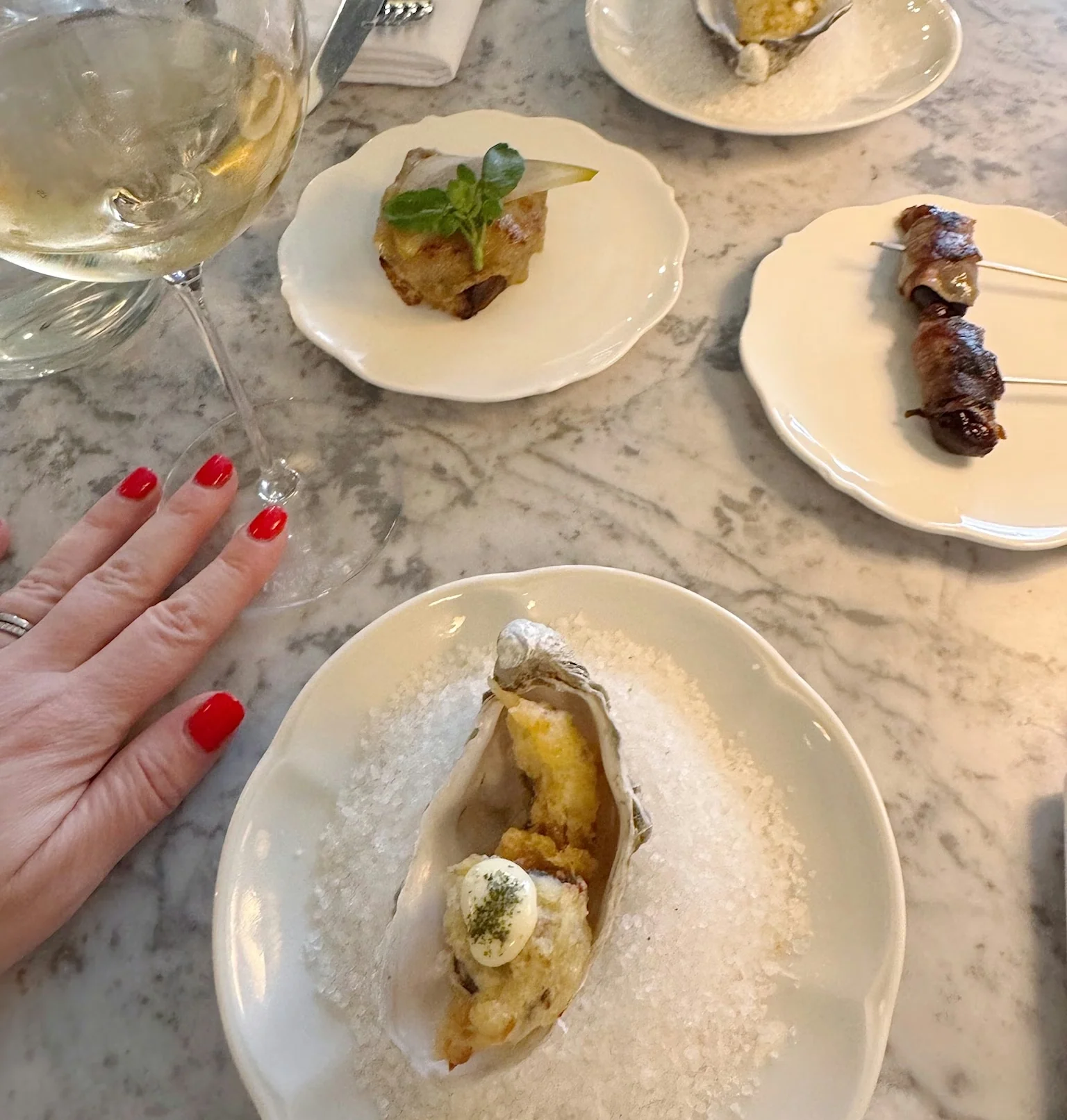 Wine glass and small plated dishes arranged on a marble table