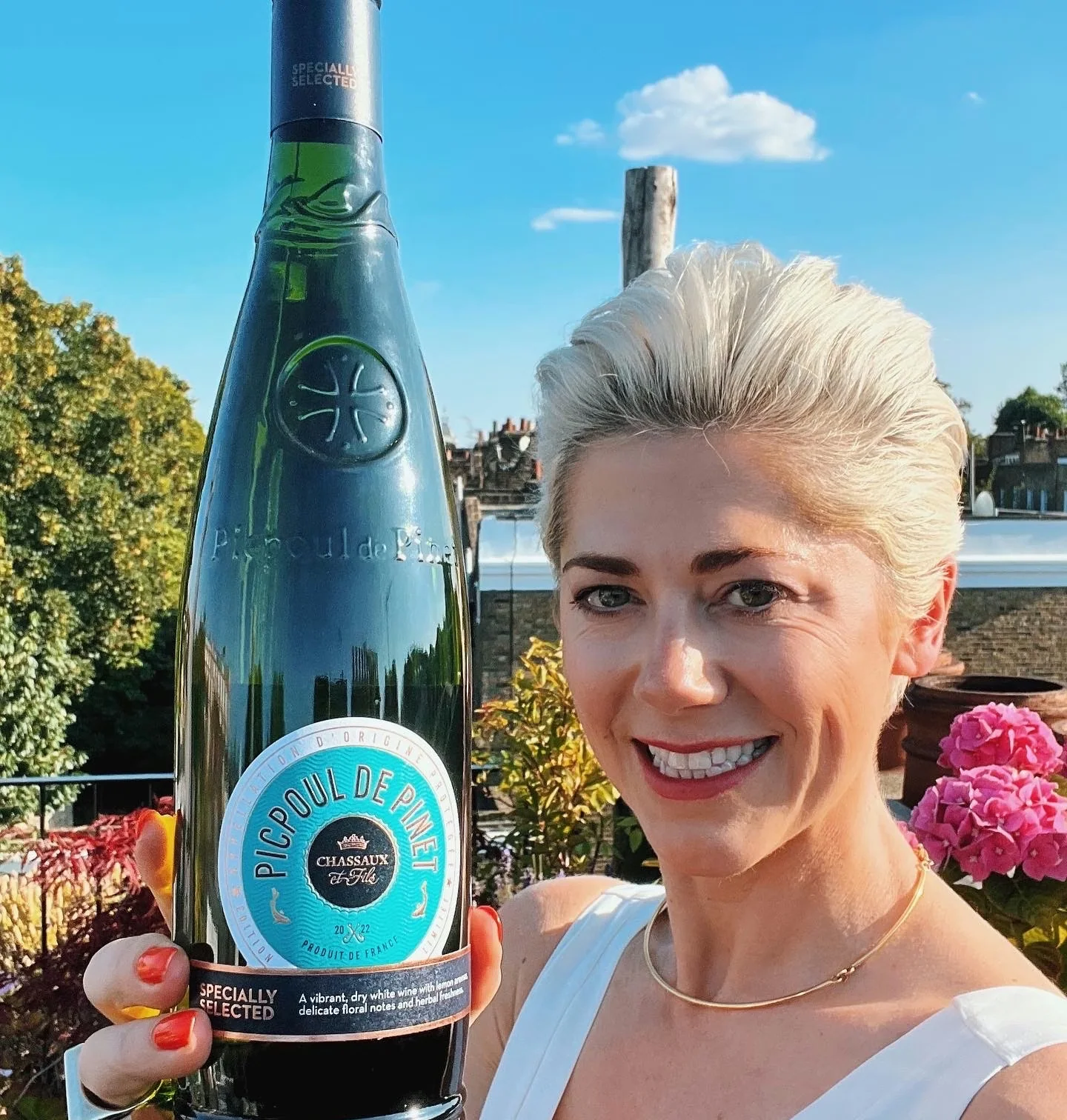 Woman holding a bottle of Picpoul de Pinet wine outdoors