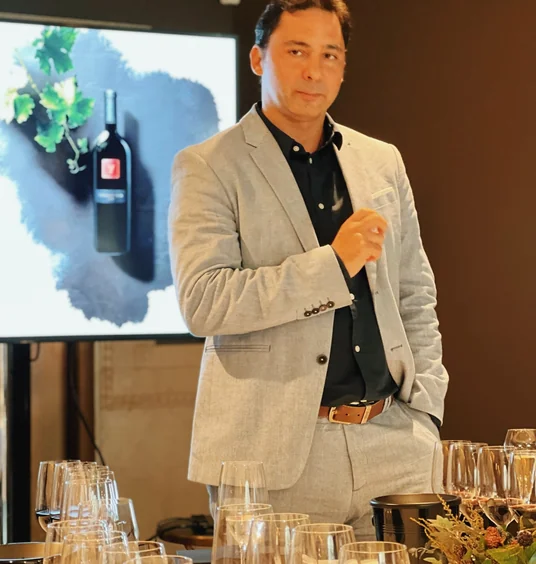 Wine presenter standing behind a tasting table in front of a bottle display