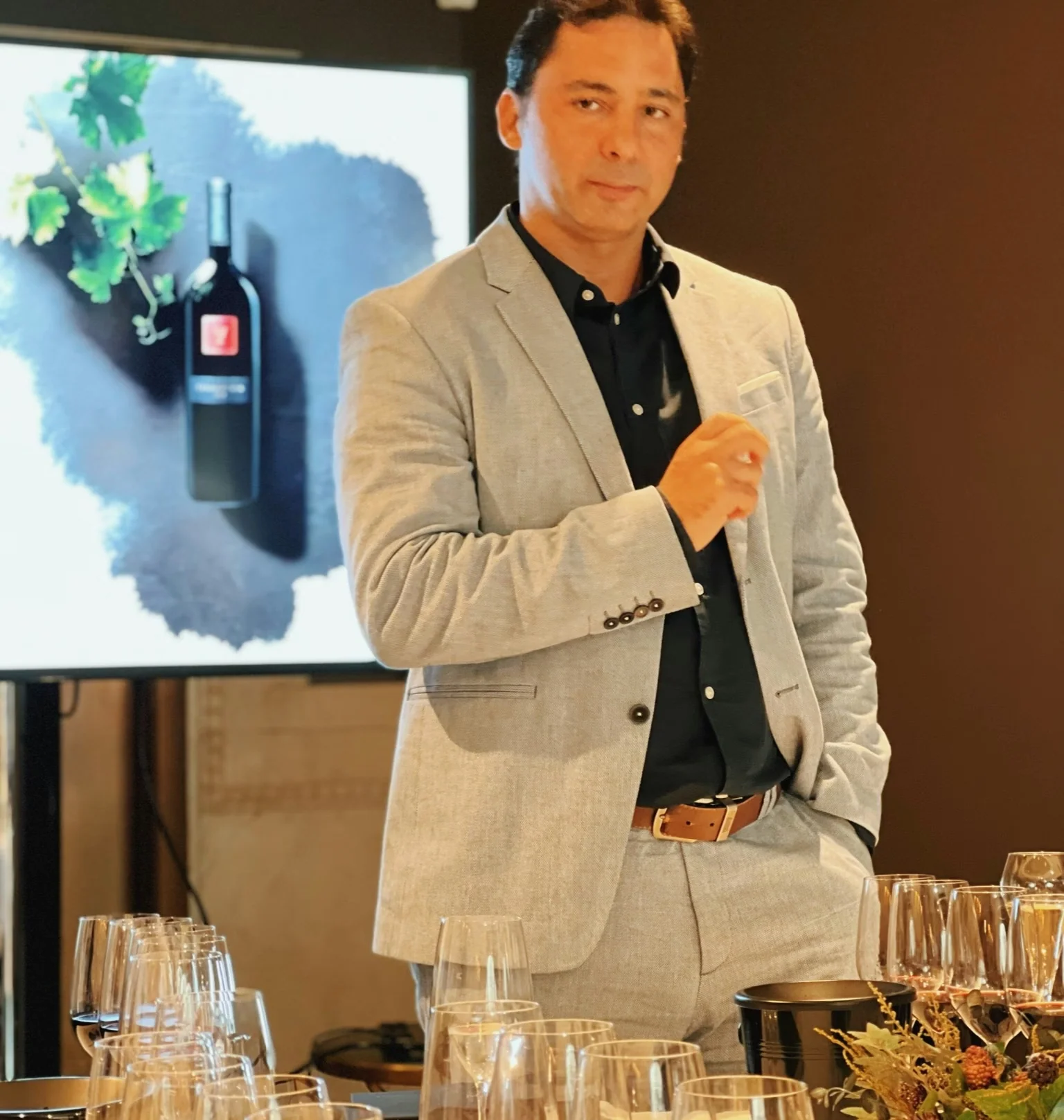 Wine presenter standing behind a tasting table in front of a bottle display