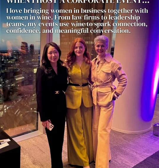 Three women pose at a corporate event beside a window overlooking the city