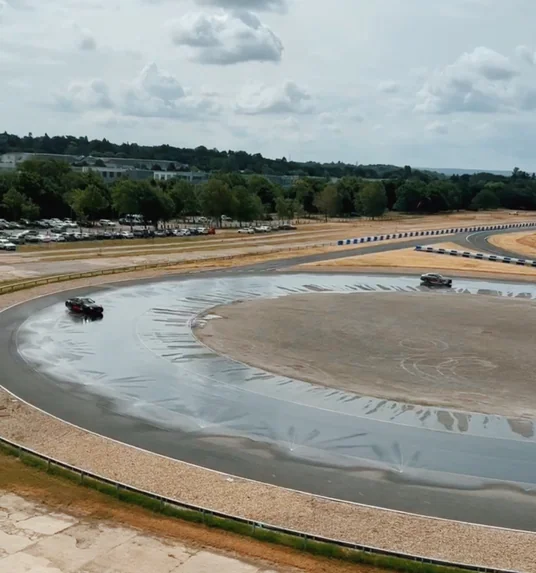 Cars driving around a wet skid pan at Mercedes-Benz World