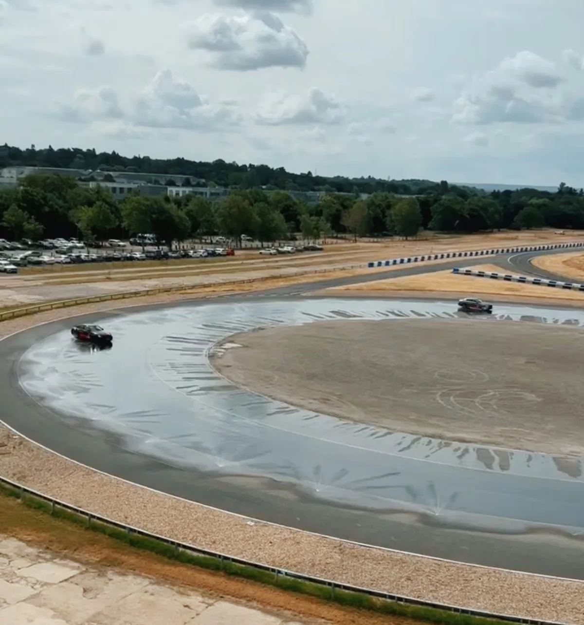 Cars driving around a wet skid pan at Mercedes-Benz World