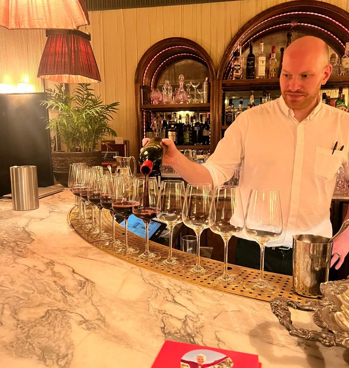 Bartender pours red wine into glasses at Kettner’s Champagne Bar