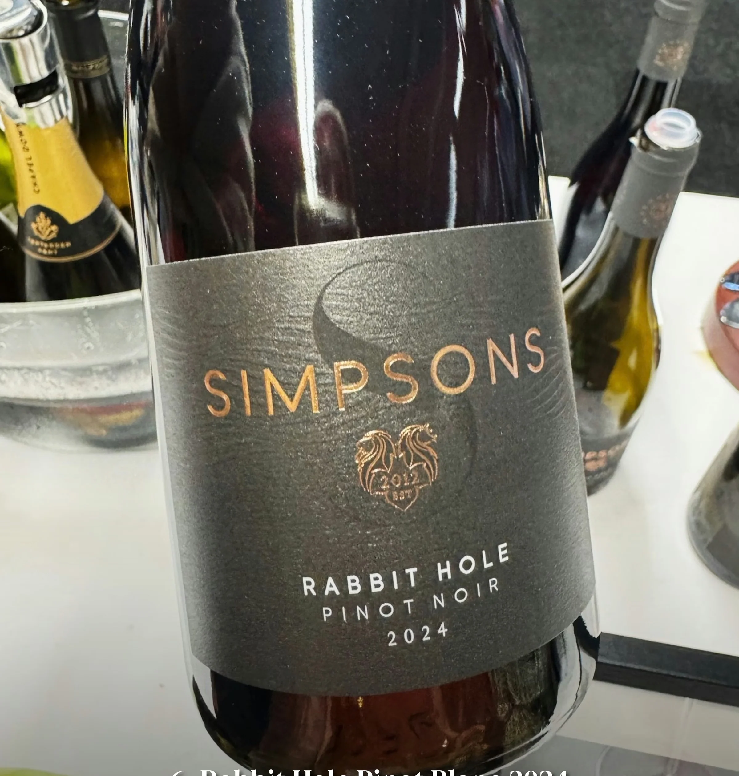 Bottle labelled Simpsons Rabbit Hole Pinot Noir 2024, with other wine bottles behind it