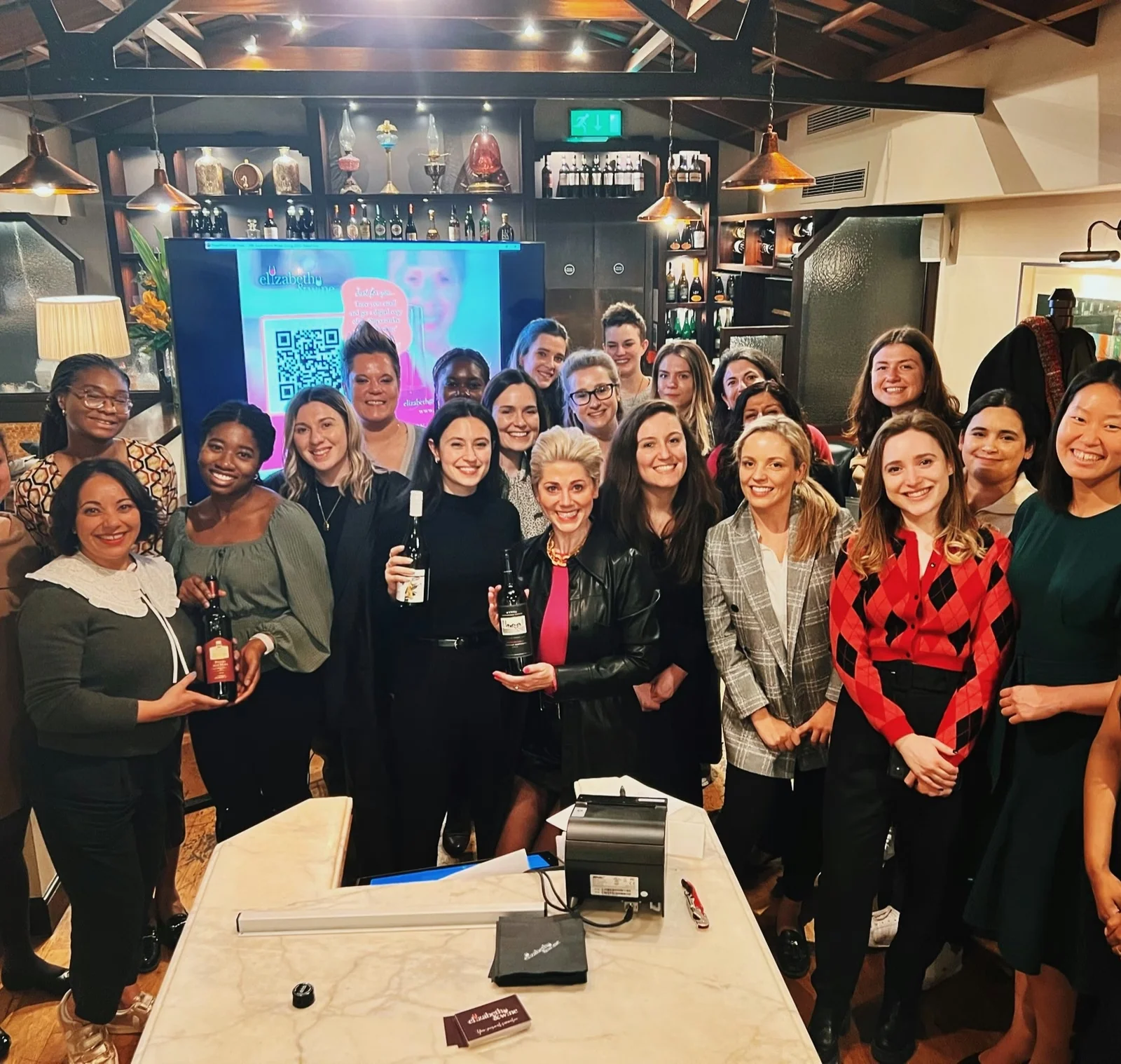 Group of guests holding wine bottles at a wine tasting in a bar