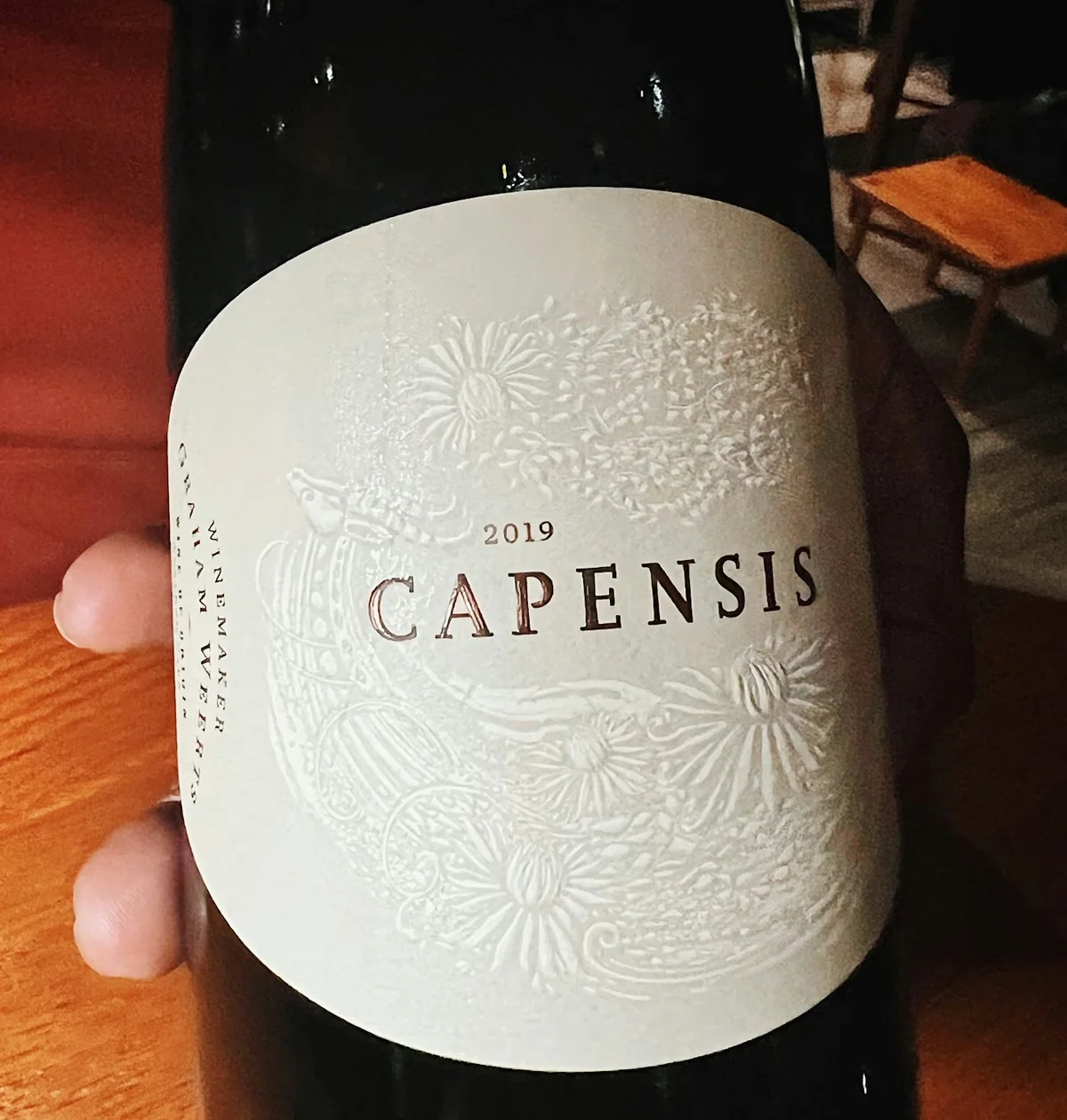 Close-up of a 2019 Capensis wine bottle with a white floral label