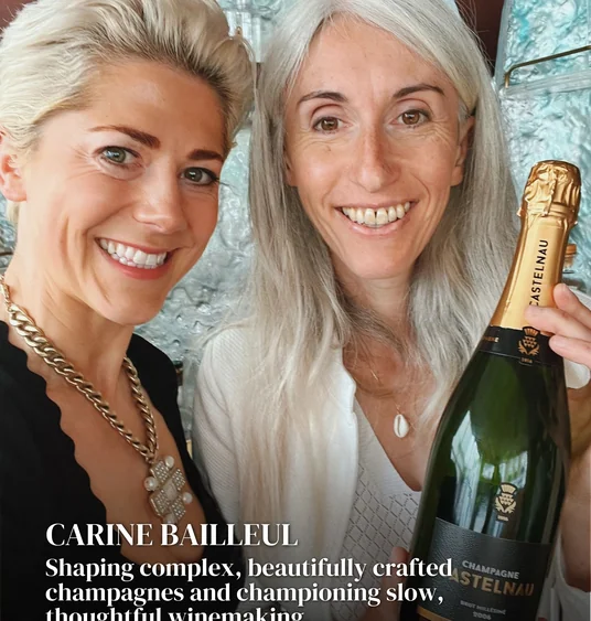 Two smiling women pose with a bottle of Champagne Castelnau beneath a Women in Wine text overlay