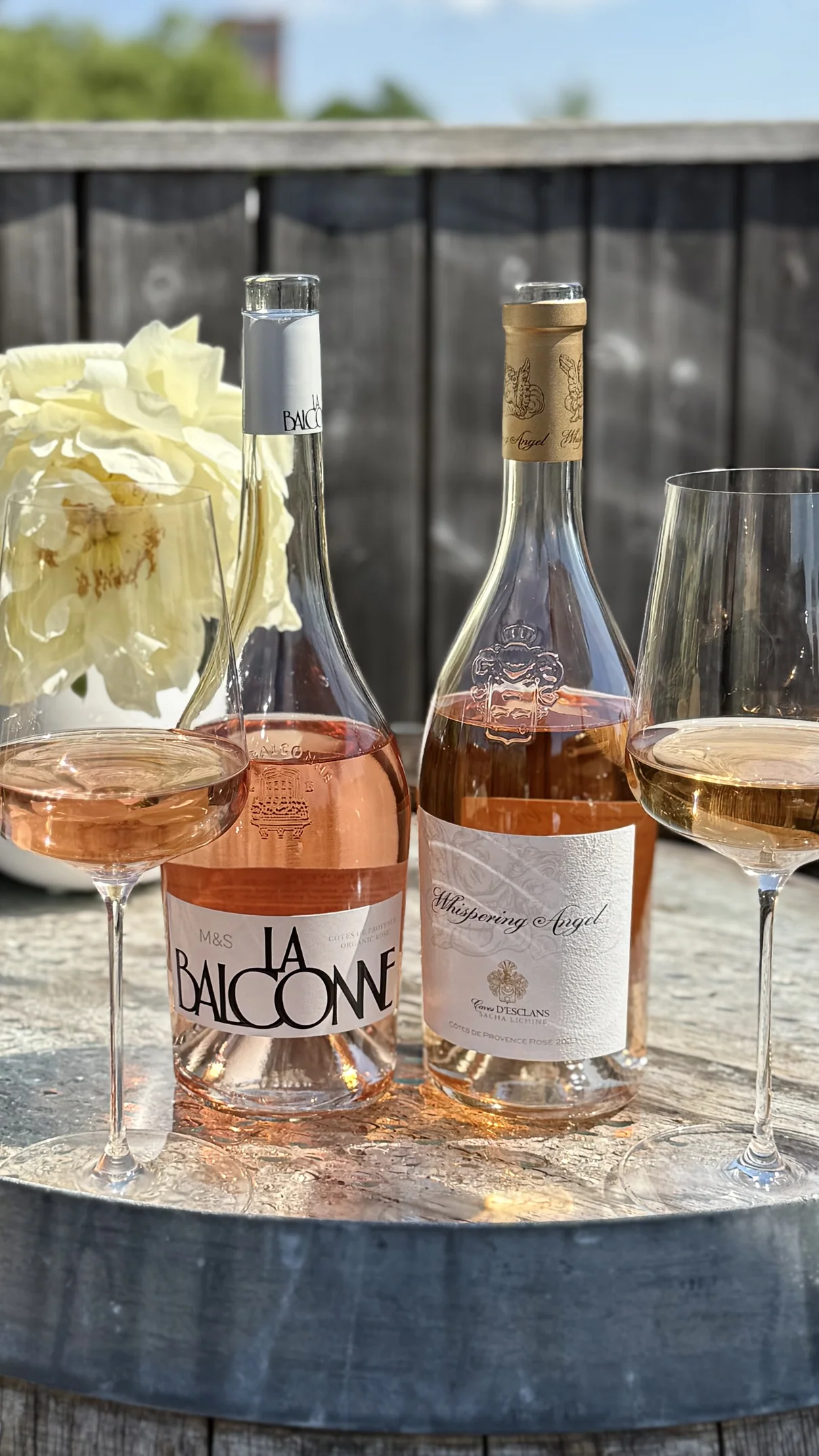 Two bottles of rosé with glasses on a garden table