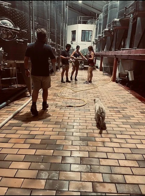People touring a winery courtyard between stainless steel tanks