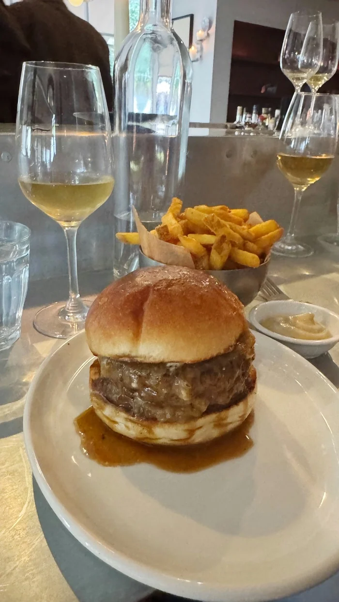 Burger, chips and white wine at a restaurant table