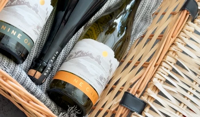 Wine bottles in a wicker hamper with labelled gift packaging