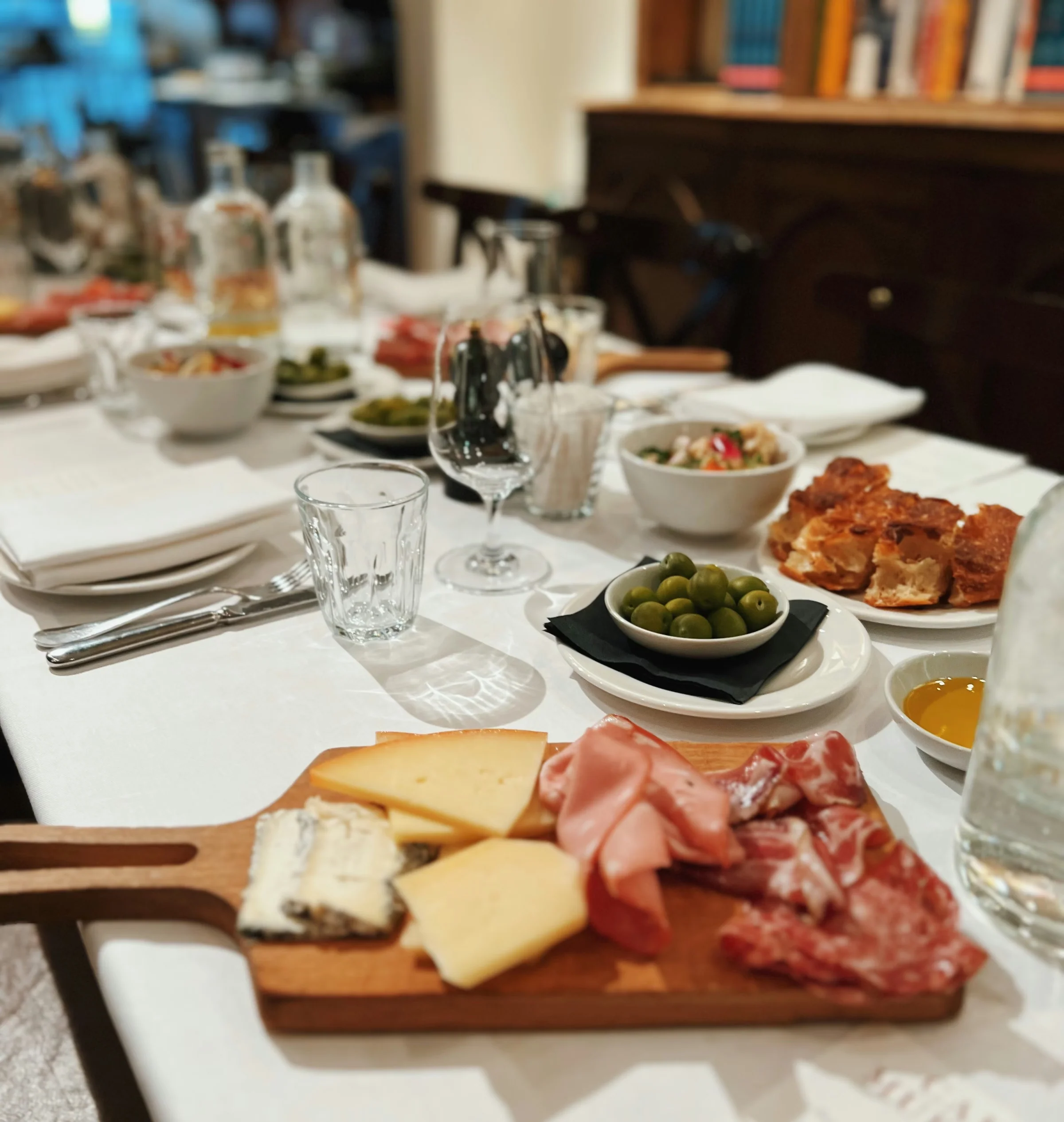 Restaurant table set with wine glasses, olives, bread, cheese and cured meats