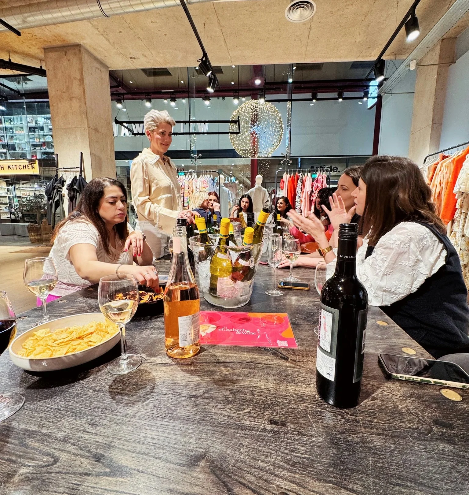 Guests tasting wine around a table in a stylish retail venue