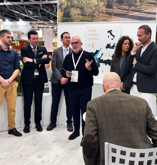 A group listens to a speaker at the Lake Garda Lands stand at Wine Paris.