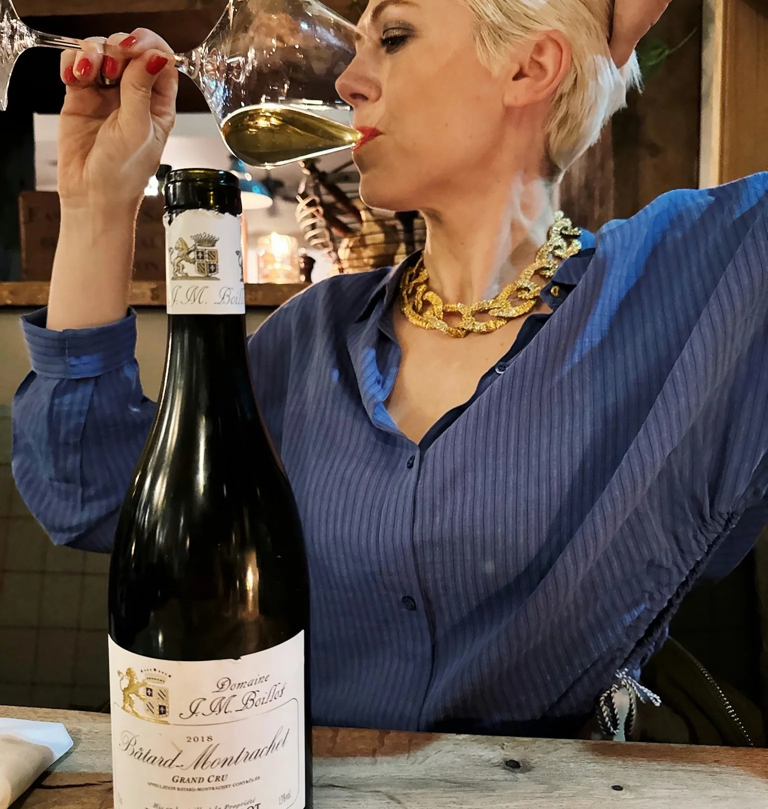 Woman tasting white wine beside a bottle of Domaine Jean-Marc Boillot Batard-Montrachet