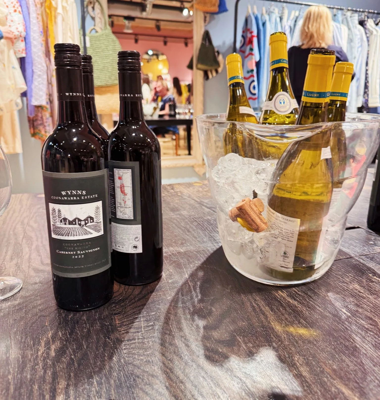 Wine bottles displayed on a wooden table, including Wynns Coonawarra Estate Cabernet Sauvignon 2022