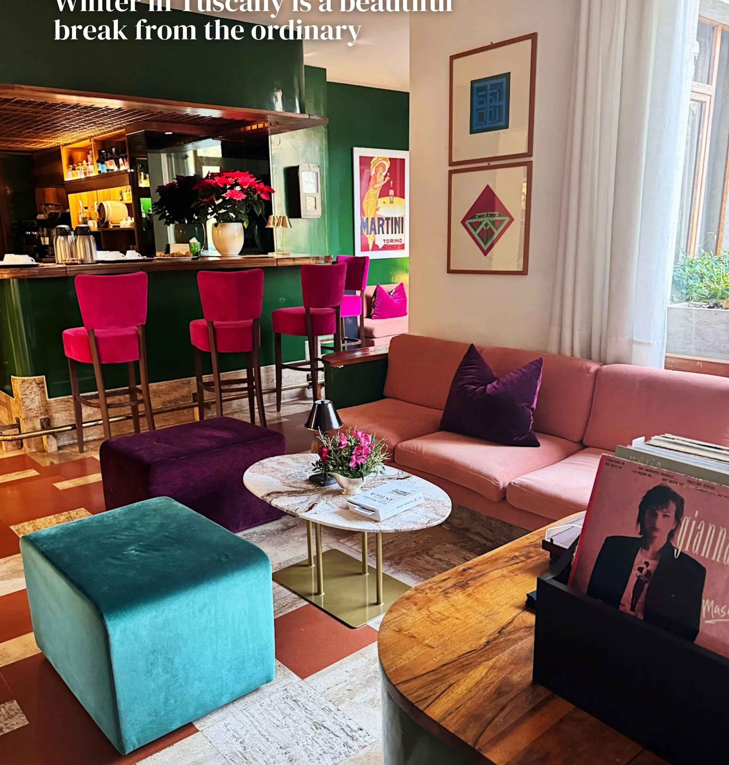 Colourful hotel lounge with a bar, pink seating, floral arrangements and vintage Martini artwork