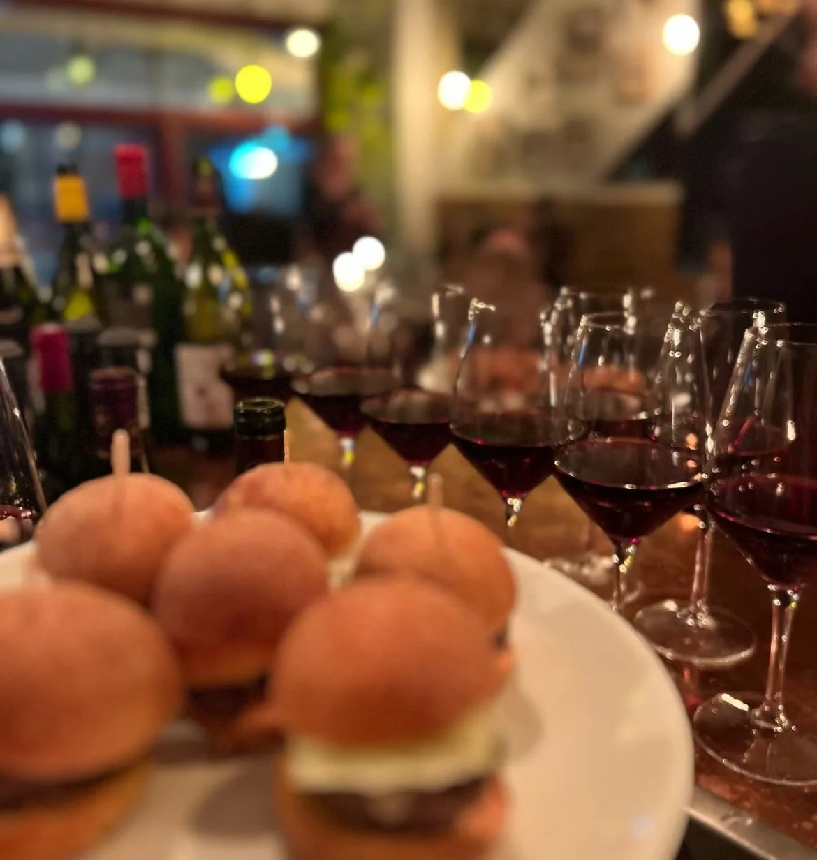 Glasses of red wine and small burgers on a plate at Lady of the Grapes
