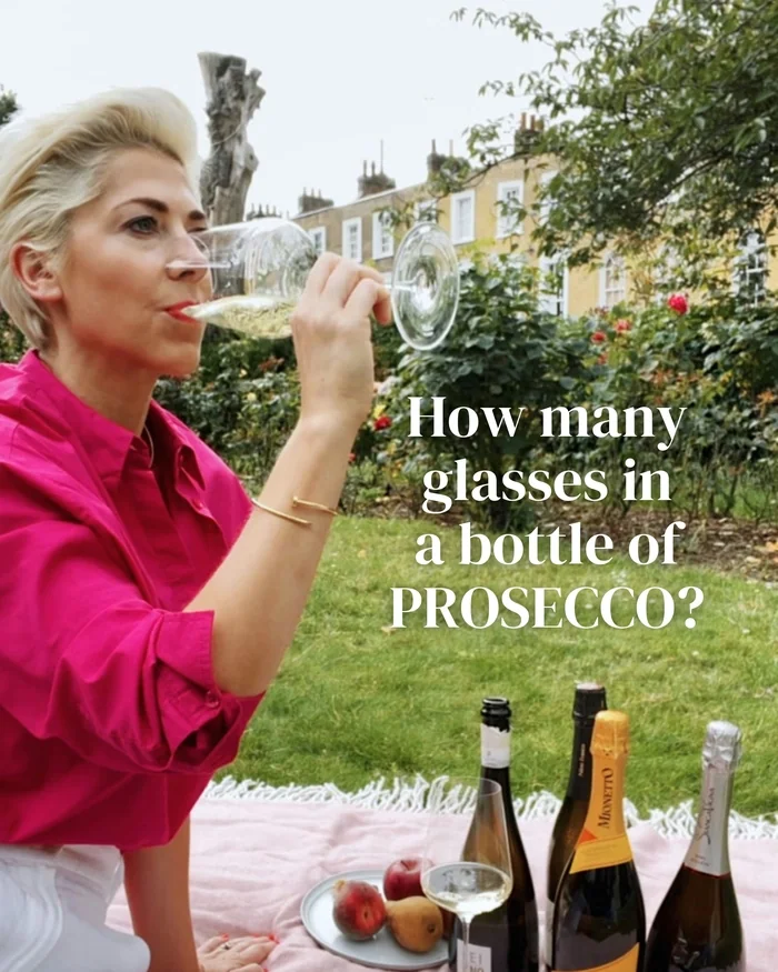 Woman drinking prosecco in a garden with bottles and fruit nearby