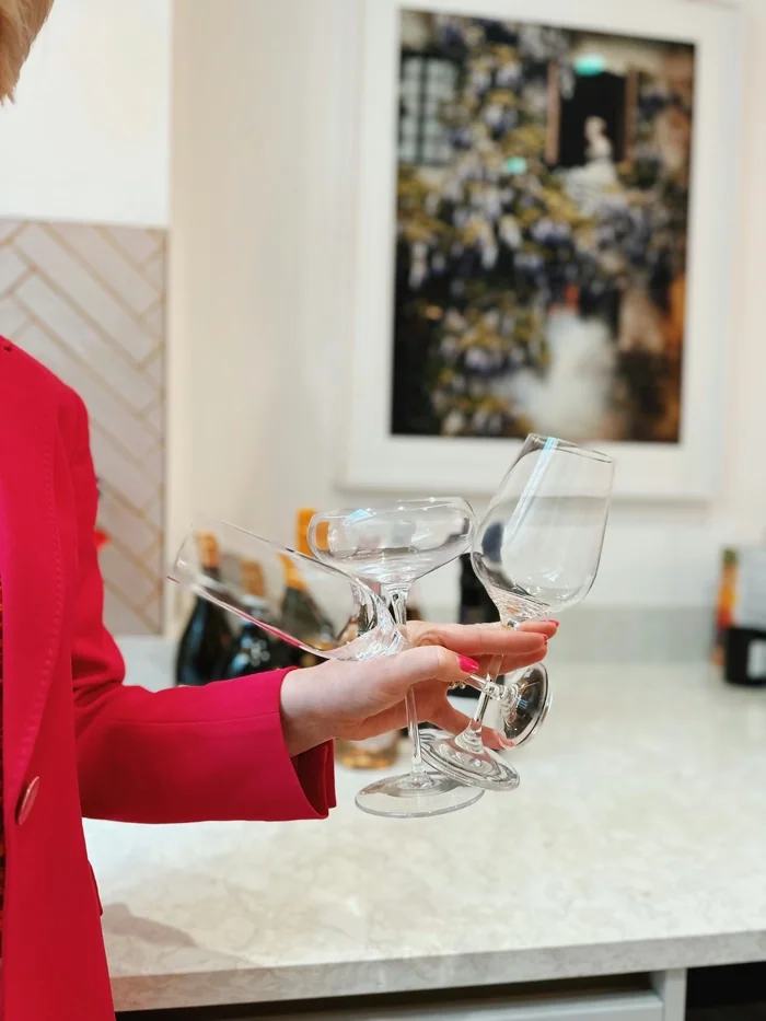 Hand holding three empty wine glasses in red sleeve