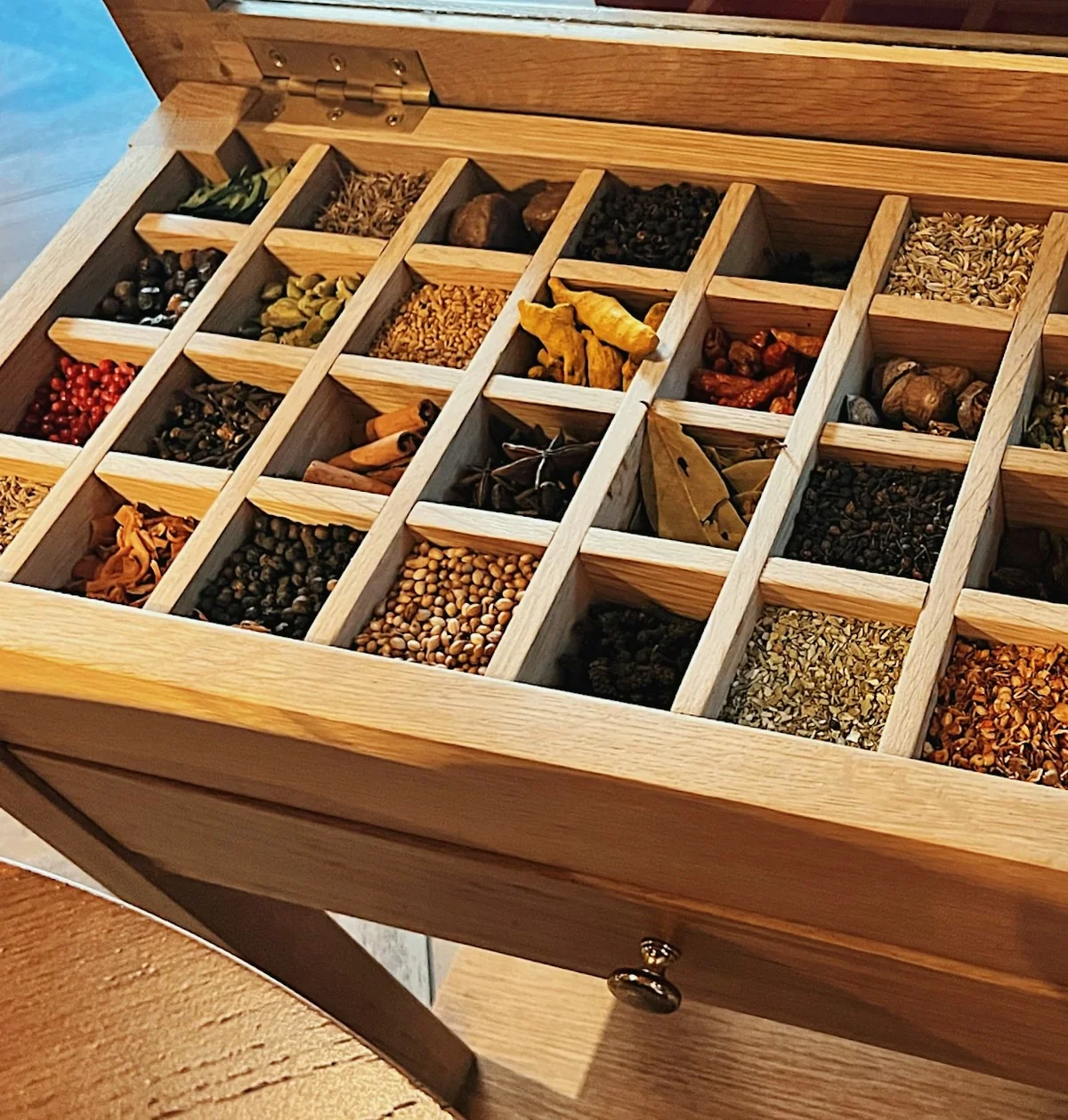 Open wooden spice chest filled with colourful herbs, seeds and dried spices