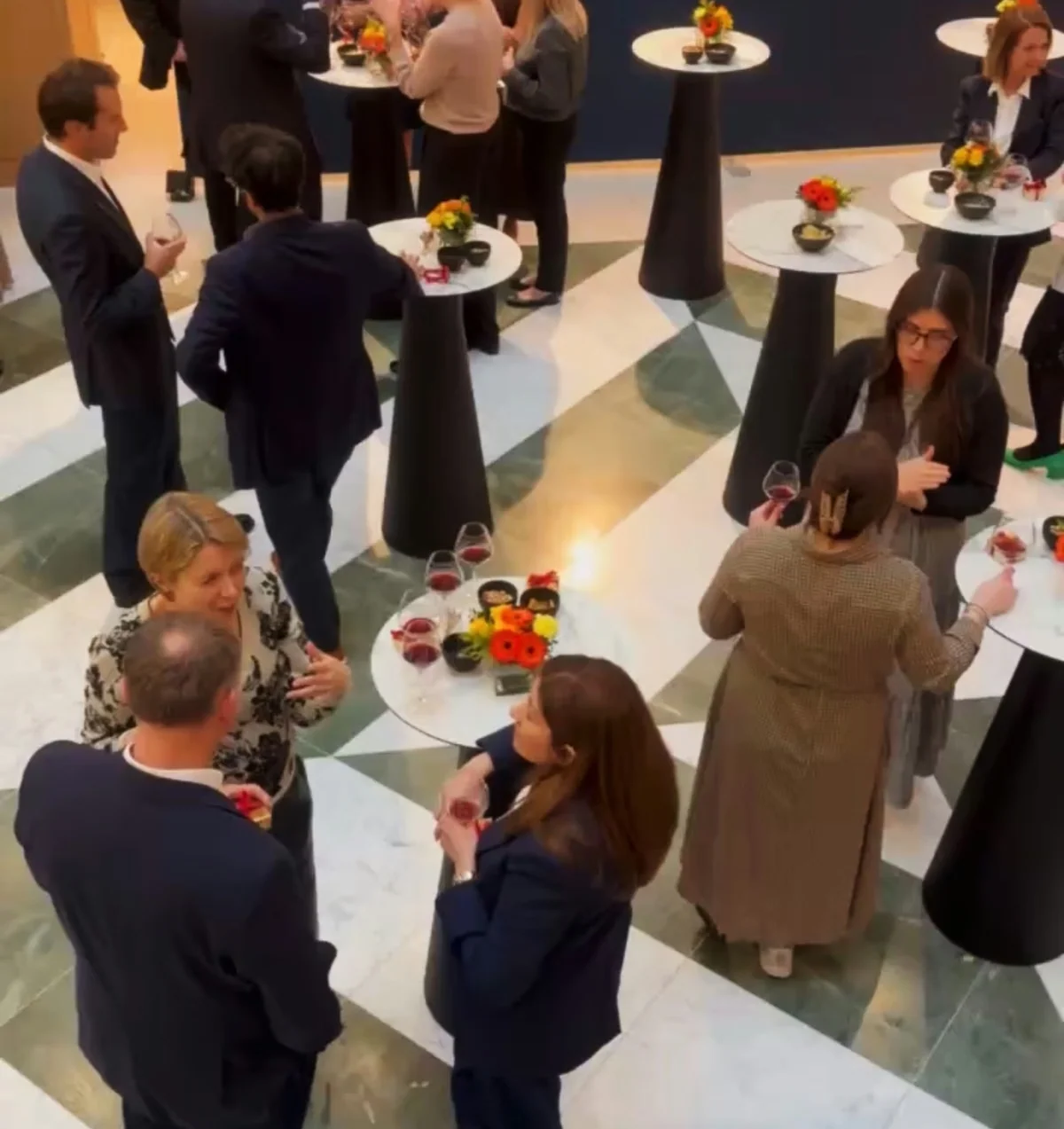 Corporate wine tasting in a London office, with guests talking around cocktail tables and holding wine glasses