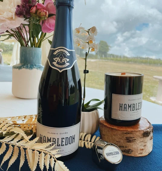 Hambledon Vineyard sparkling wine bottle and candle beside flowers by a window