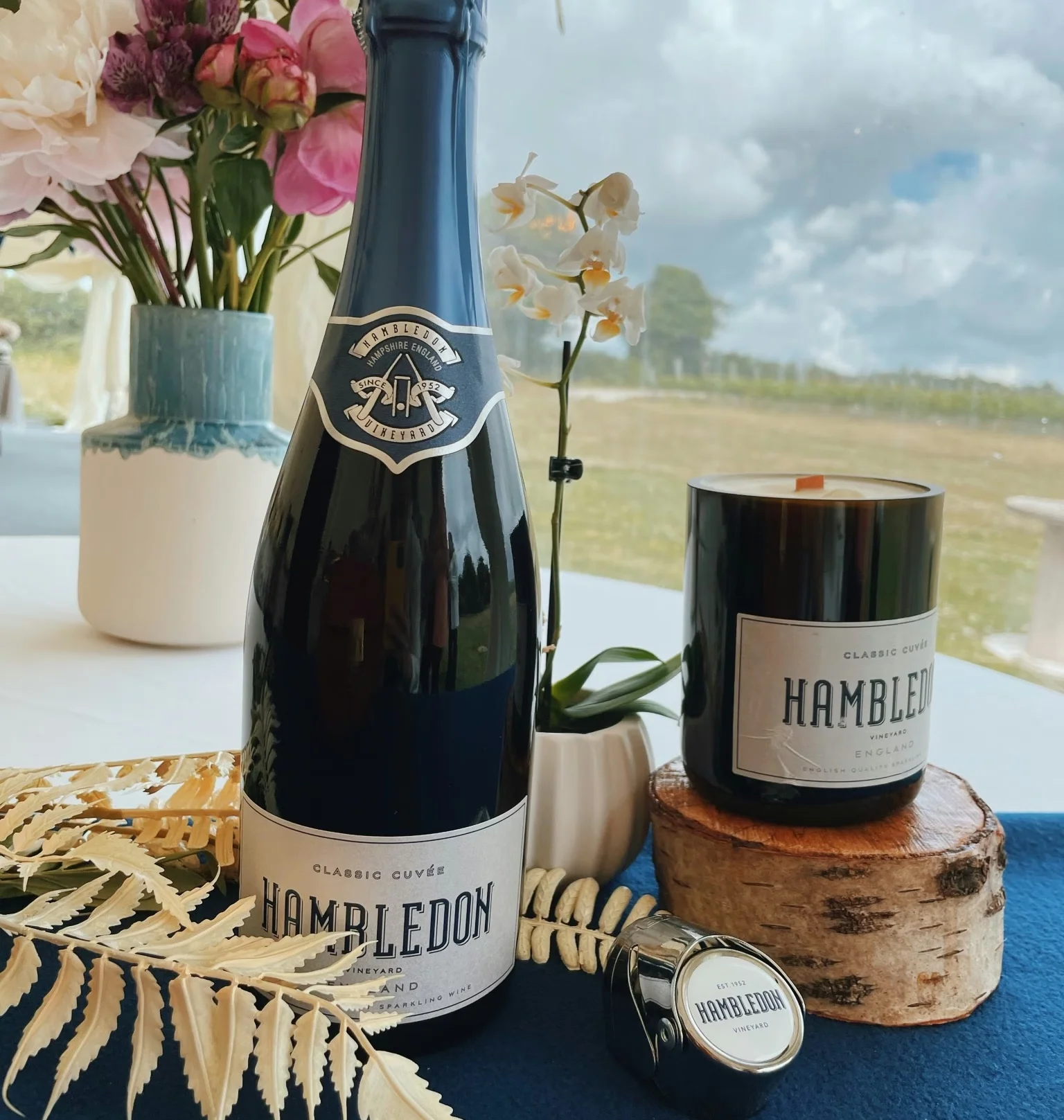 Hambledon Vineyard sparkling wine bottle and candle beside flowers by a window