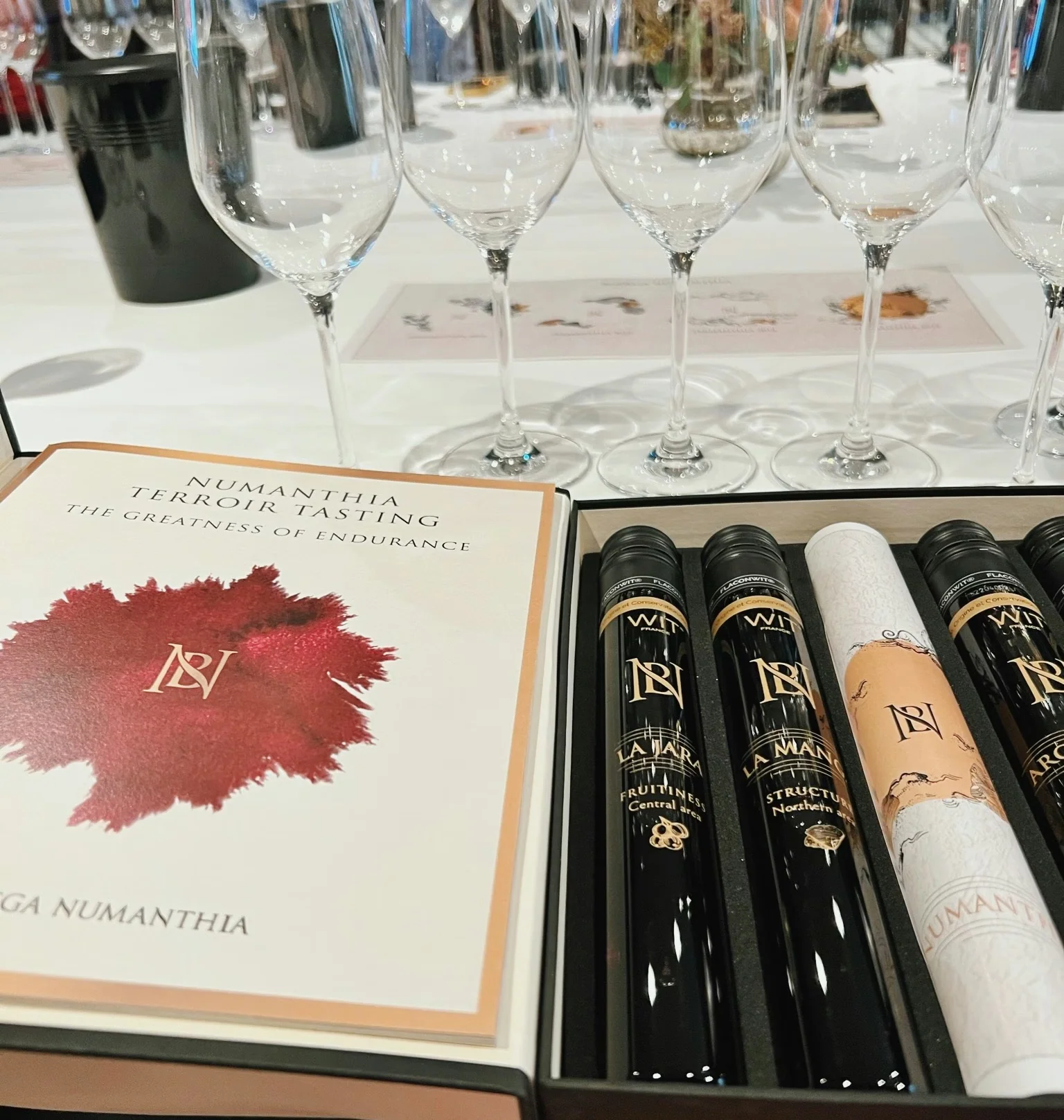 Numanthia terroir tasting box with wine bottles and rows of empty glasses