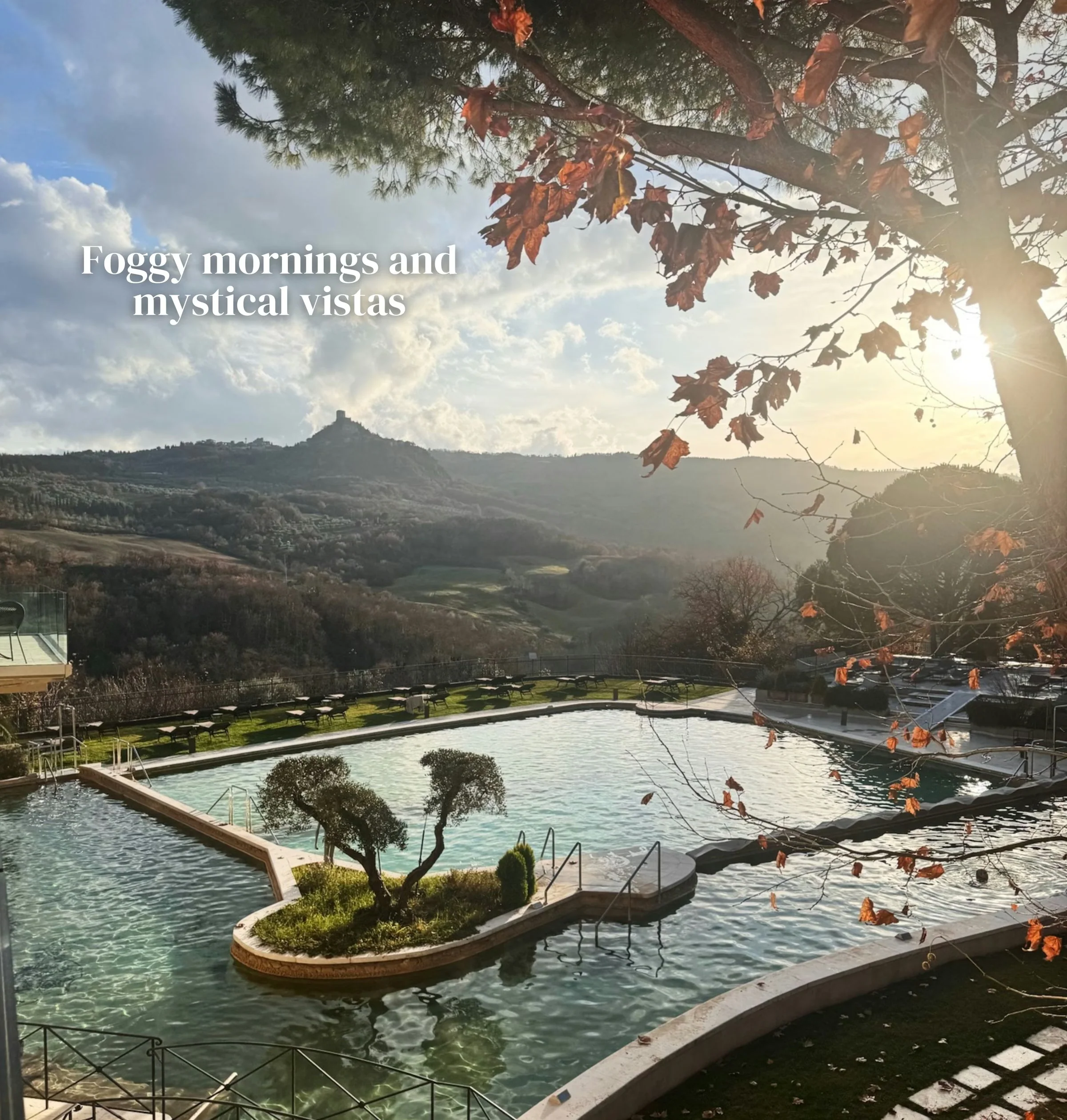 Thermal pools overlooking a Tuscan hillside beneath autumn trees and a bright morning sky