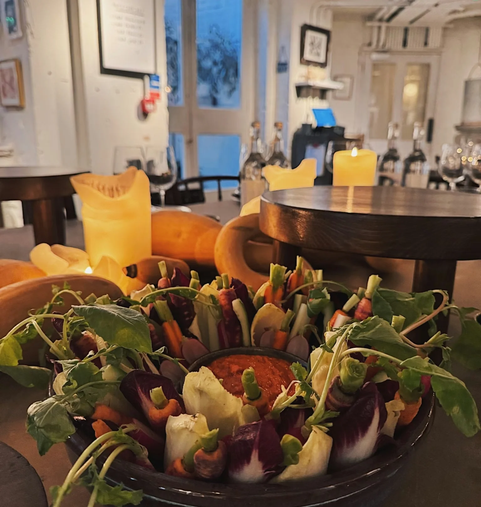 Vegetable crudités and dip beside candles in a warmly lit dining room